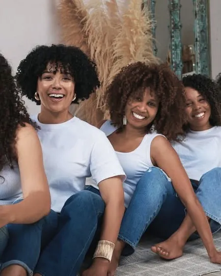 Clientes aux cheveux afro naturels, assises en jean, qui rient ensemble au salon de Montréal