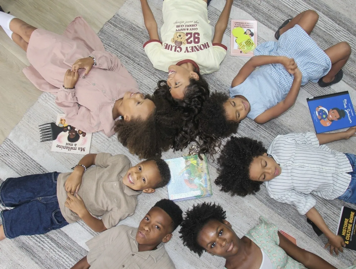 Types de cheveux bouclés chez l’enfant : enfants aux cheveux bouclés et crépus allongés en cercle avec des livres